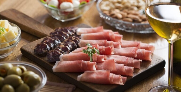 Tagliere di salumi e formaggi con bicchiere di vino.