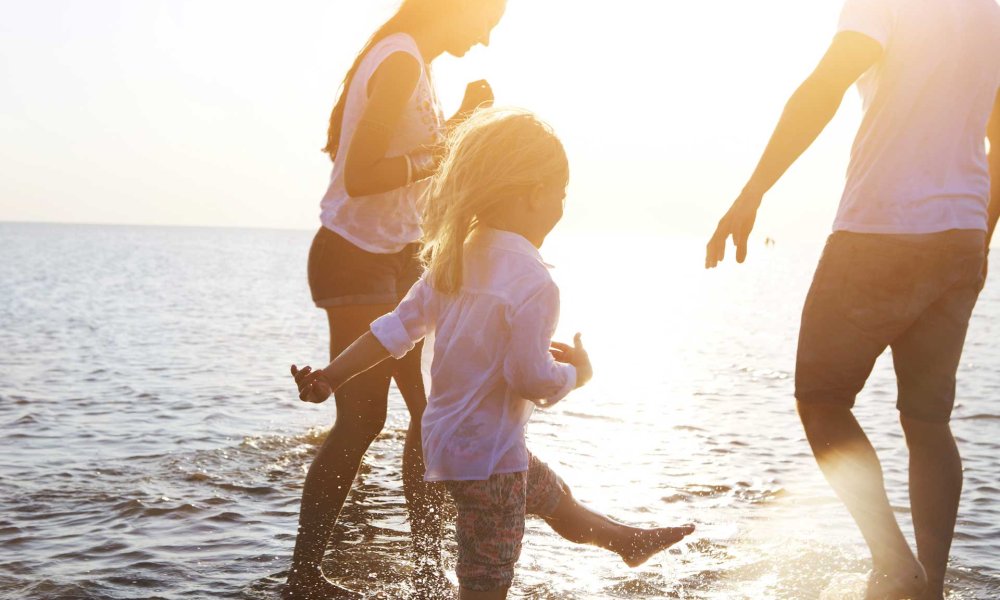 Famiglia che cammina sulla spiaggia al tramonto.