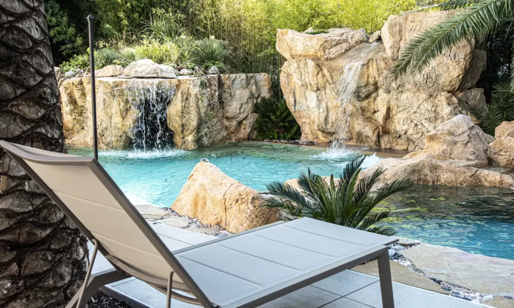 Sdraio vicino a una piscina con cascata e rocce naturali.