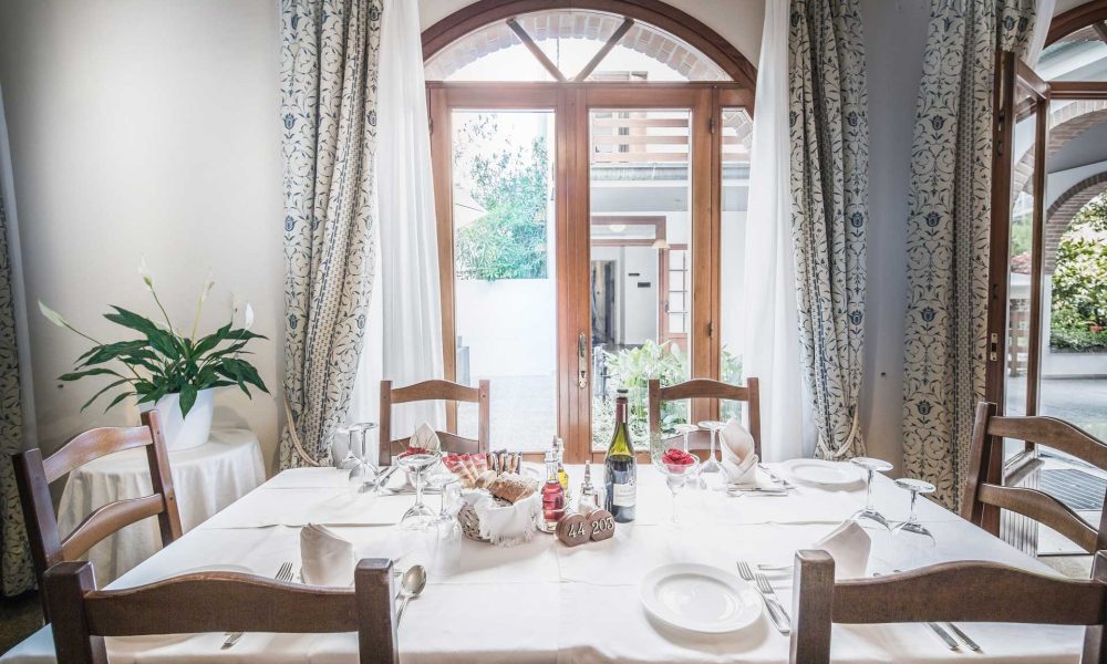 Tavolo apparecchiato in una sala da pranzo elegante con vista sul giardino.